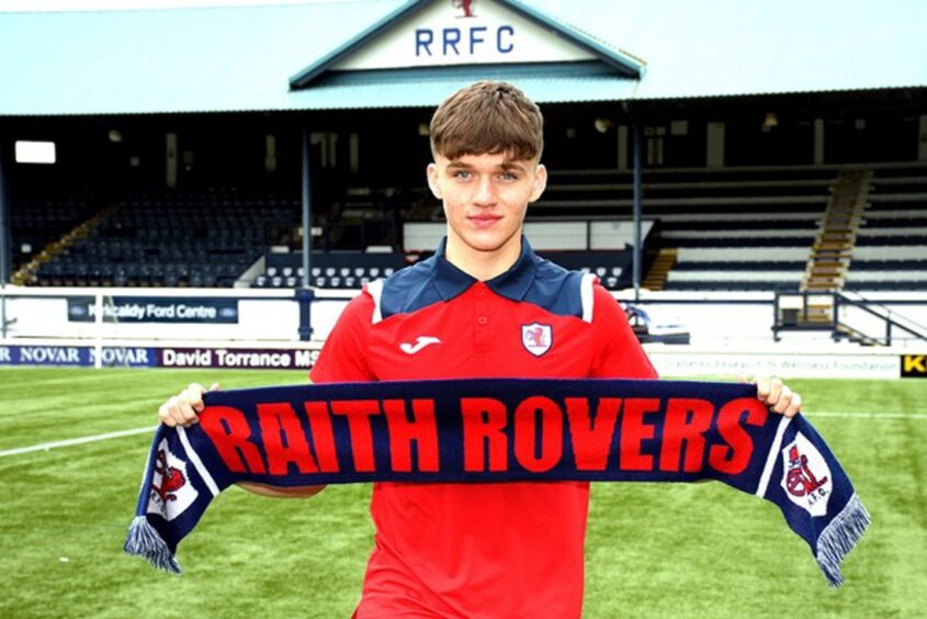 Kai Montagu holds up a Raith Rovers scarf in front of the Stark's Park main stand.