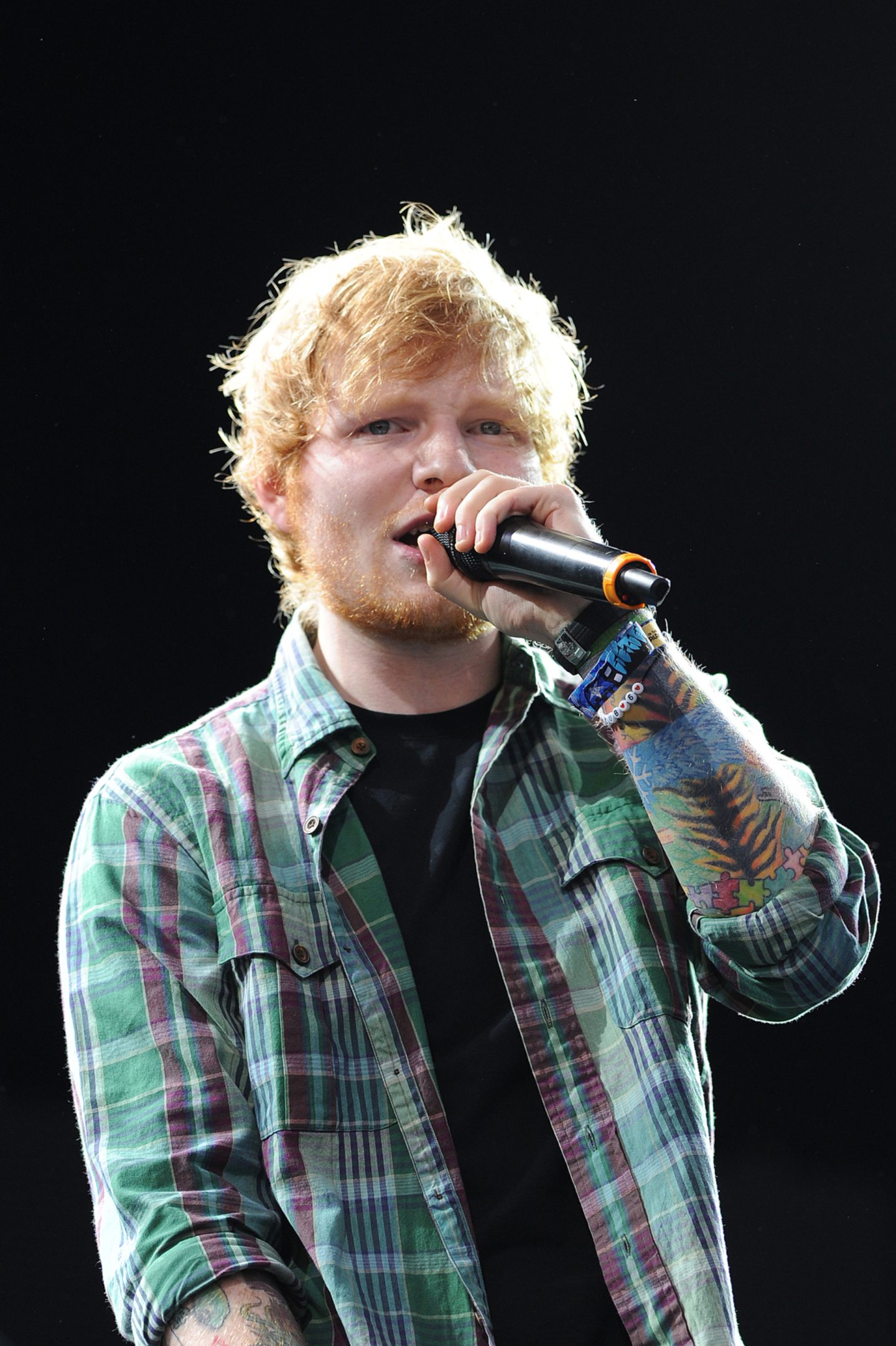 Ed Sheeran sings into a mic on stage at T in the Park in 2014