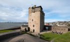 Image shows: an exterior view of Broughty Castle. The imposing castle tower sits against a grey Tay Estuary and cloudy blue sky. For summer castles feature.