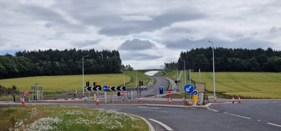 New roundabout with grass covered pedestrian bridge in distance