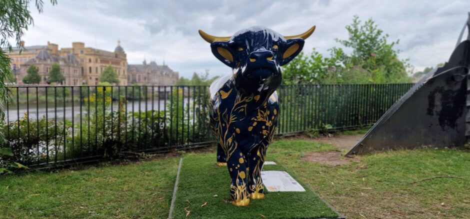 Cow sculpture beside river Tay with Perth skyline behind