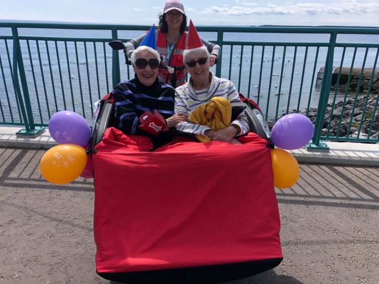 Best friends Agnes Stewart and Nancy Delaney enjoy a birthday celebration on the trishaw with volunteer pilot Barbara.