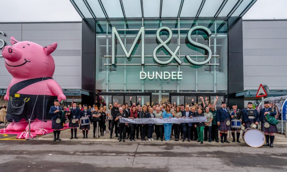 Staff celebrating the opening day of Dundee M&S with a pipe band and giant Percy Pig.