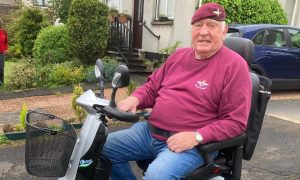 Charlie Lennon in Parachute regiment sweatshirt and beret seated on mobility scooter outside his Perth home