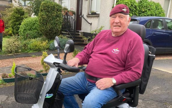 Charlie Lennon in Parachute regiment sweatshirt and beret seated on mobility scooter outside his Perth home