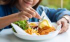 woman adds garnish to a plate of fish and chips in Fife