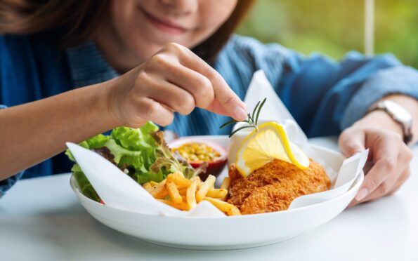 woman adds garnish to a plate of fish and chips in Fife