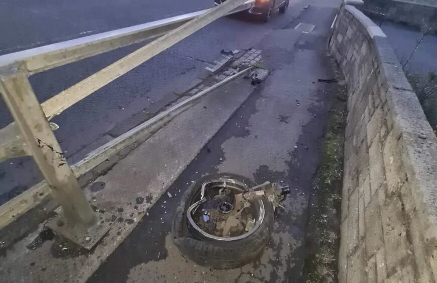 A detached wheel from the car and the damaged barriers.