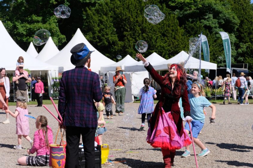 Children and adults playing with bubbles at Scone garden fair
