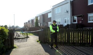 A police officer standing guard in Whitfield Avenue, Dundee, in March 2022.