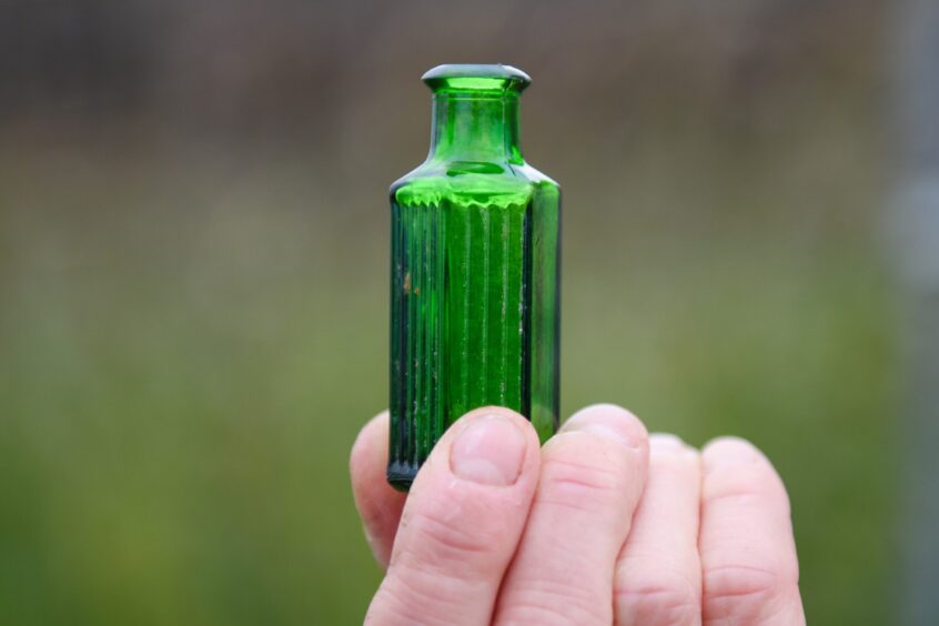 Carol Evans with a Second World War German pilot's poison bottle found in a midden on the dunes at Lunan Bay. Image: Kim Cessford. 