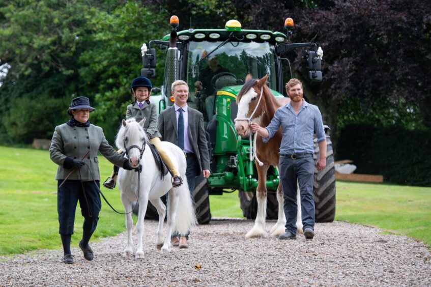 Group of people with small child on pony, Clydesdale horse and tractor