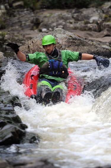 Image shows: An outdoor adventure instructor braves the white water in an inflatable 'river bug'.