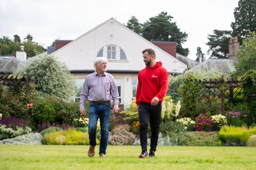 Grant Laing and Kevin Cuthbert walking across lawn in front of Rodney Pavilion