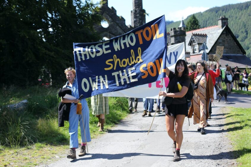 Protesters at Kenmore carrying banner which reads 'Those who toil should own the soil'.