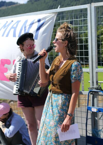 Speaker with person playing accordion behind