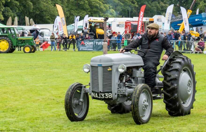 Small grey vintage tractor being ridden round show ring