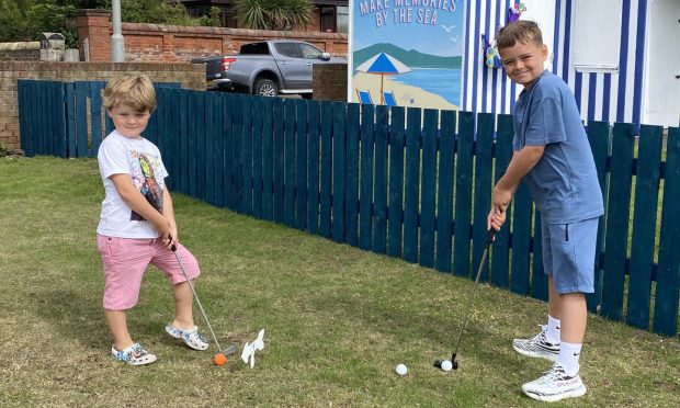 Five-year-old Michael Morris and Nathan Berry, 10, were the first to try out the new putting green. Image: Supplied by Fife Council.