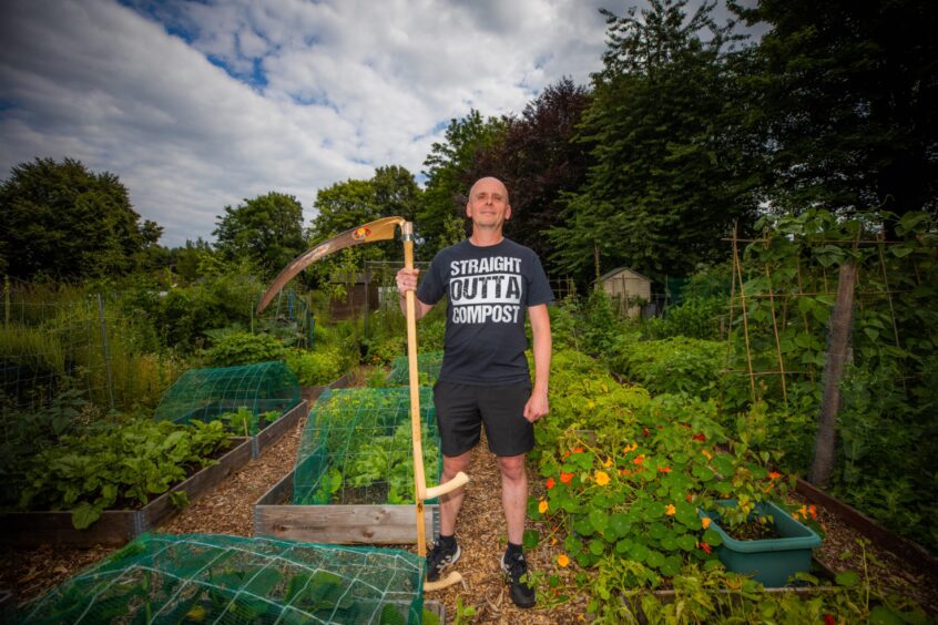 Calum Harvie complete with scythe at his allotment in Cupar.