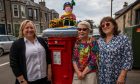 Image shows: three members of the Largo Yarnbombing Lassies, standing by a post box with one of their creations, 'Finn the pirate'.