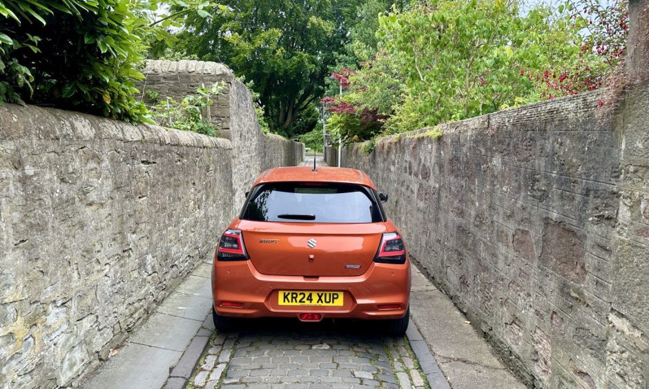 A rear shot of the car going down a narrow, cobbled Dundee lane.