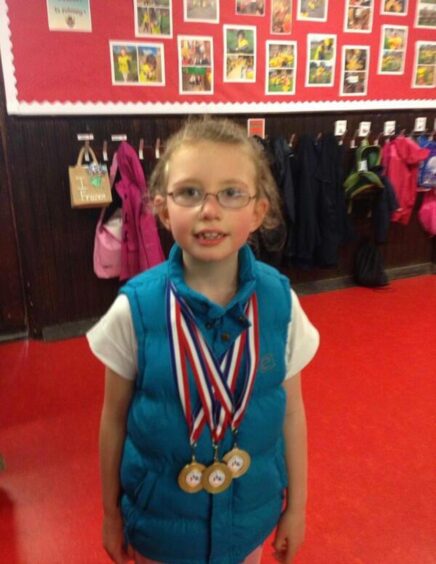 Taylor, age 7, with her three gold medals she won at the Discovery Games Dundee disability gala.