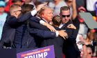 Former president Donald Trump is helped off the stage by secret service agents with blood on his face after a shooting incident at a campaign event