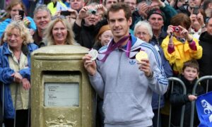 Scottish tennis player Sir Andy Murray holds up gold medals next to his gold post box in hometown Dunblane