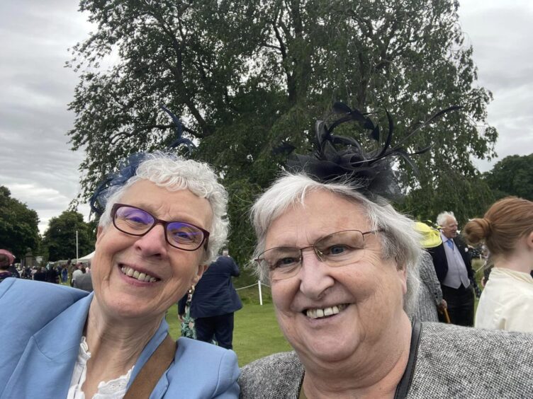 Alison Middleton and Anne Houston in fancy hats smiling for a selfie at the garden party
