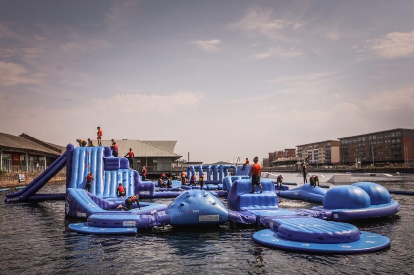 Image shows: the inflatable aqua park at Wild Shore, Dundee. The watersports centre offers this and lots of other activities for the summer holidays. The large inflatable assault course floats on the water in city quay.