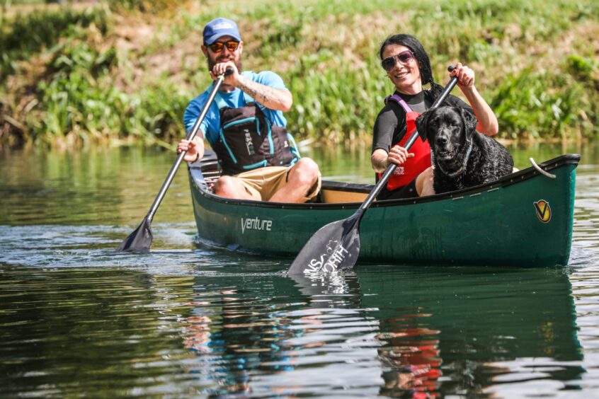 Image shows: Two people and a dog enjoying a paddle in a canoe at Willowgate Activity Centre, Perth. 