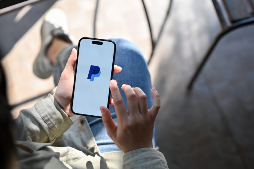 woman using PayPal application through her smartphone.