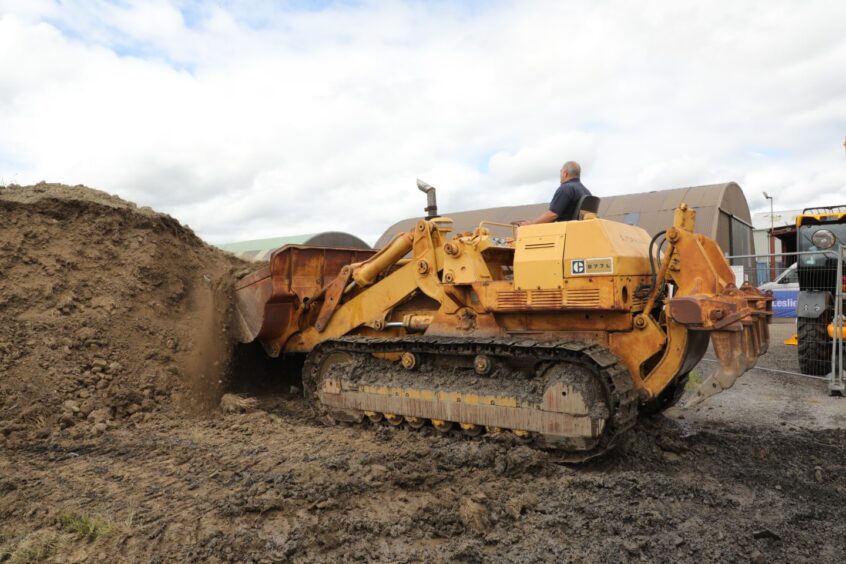 Driver moving big mound of earth on large yellow machine