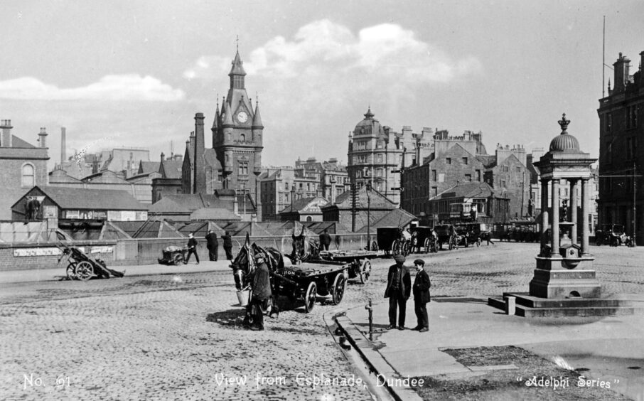 Men with their horse and cart on a city street. Dundee West Station can be seen in the background.