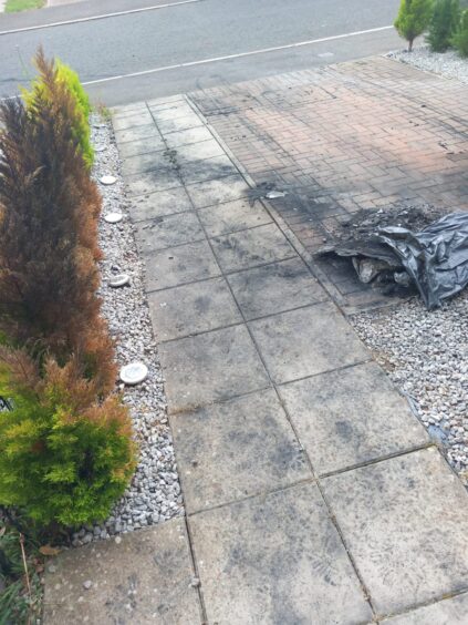 Charred pavement and burned hedge outside family home following fire