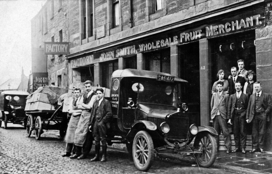 Cars are parked on the road as the staff line up outside the business. 