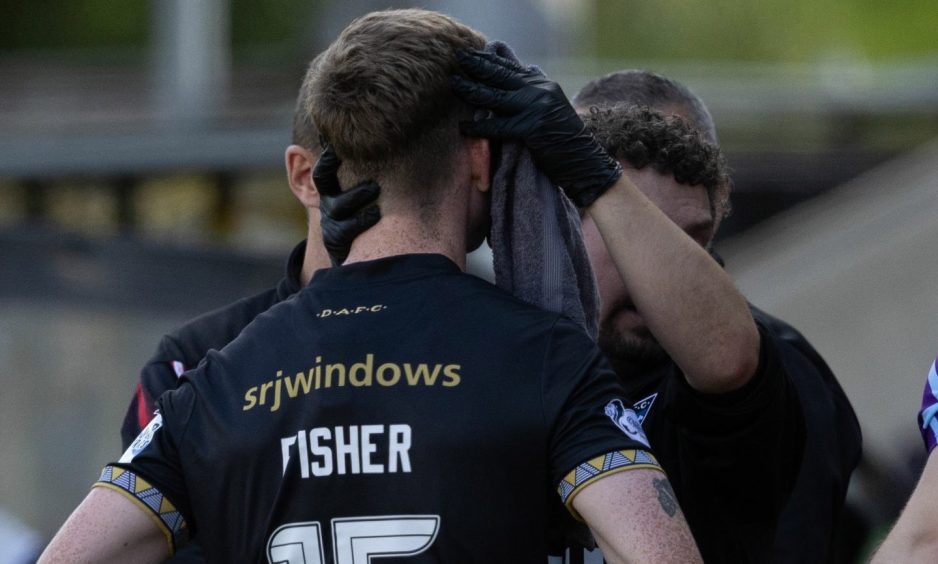 Dunfermline Athletic F.C. defender Sam Fisher receives treatment for a cut on his face.