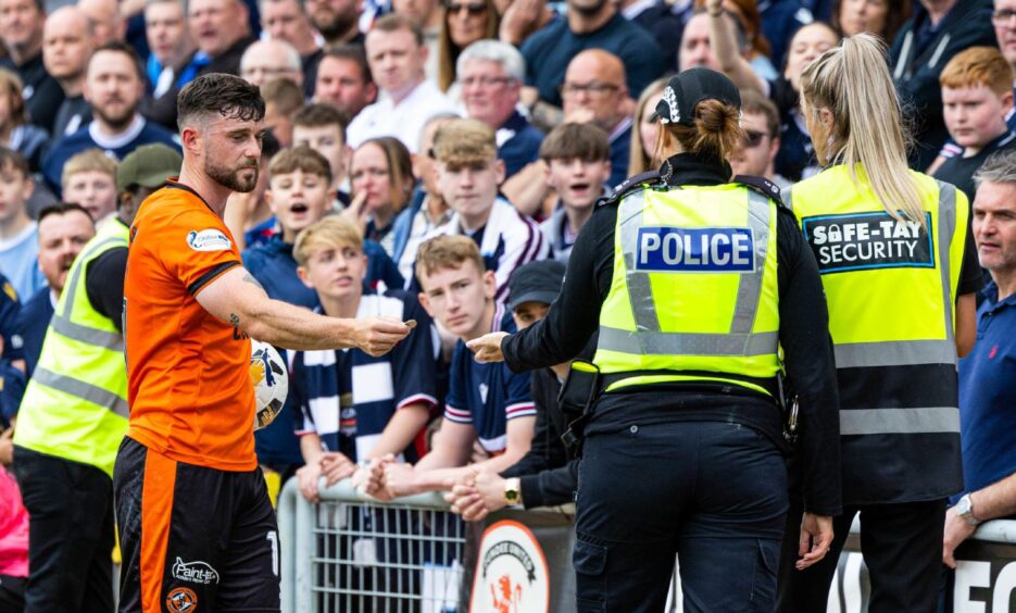 Dundee United's Will Ferry hands a coin to a police officer. Image: Ross Parker/SNS