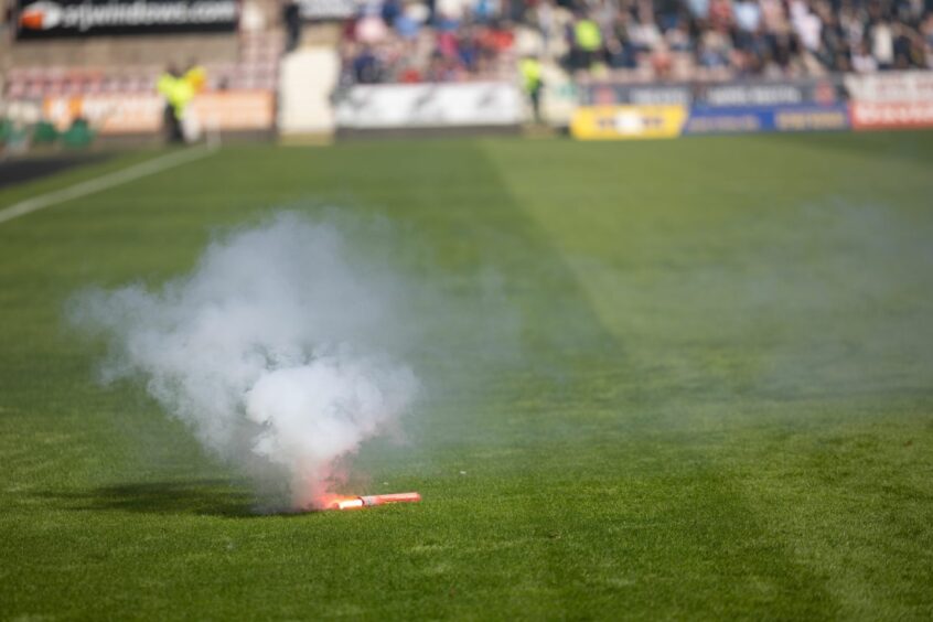 A pyrotechnic thrown from the Pars end lies on the East End Park pitch.