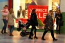 Crowds walking past shop window with sales posters in St John's shopping centre