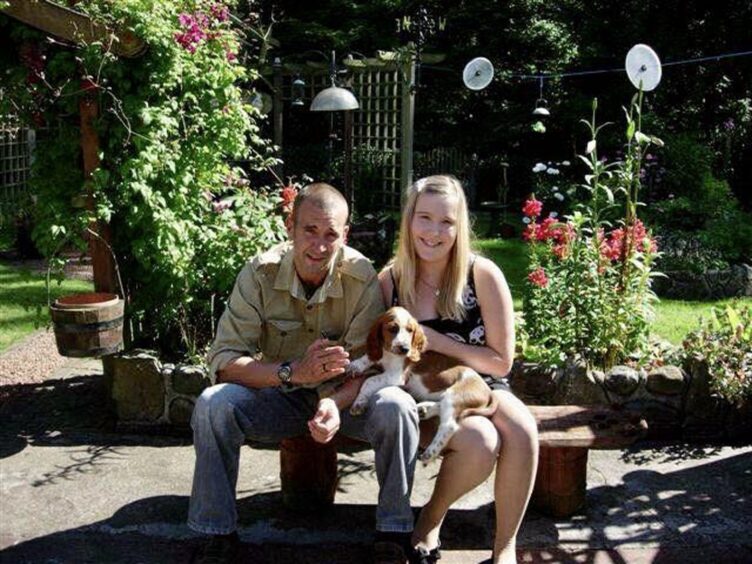 David Haines seated on bench with teenage daughter Bethany by his side and a puppy on her lap