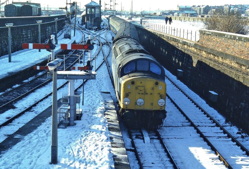 The Glasgow to Dundee train moves along with snow on the tracks