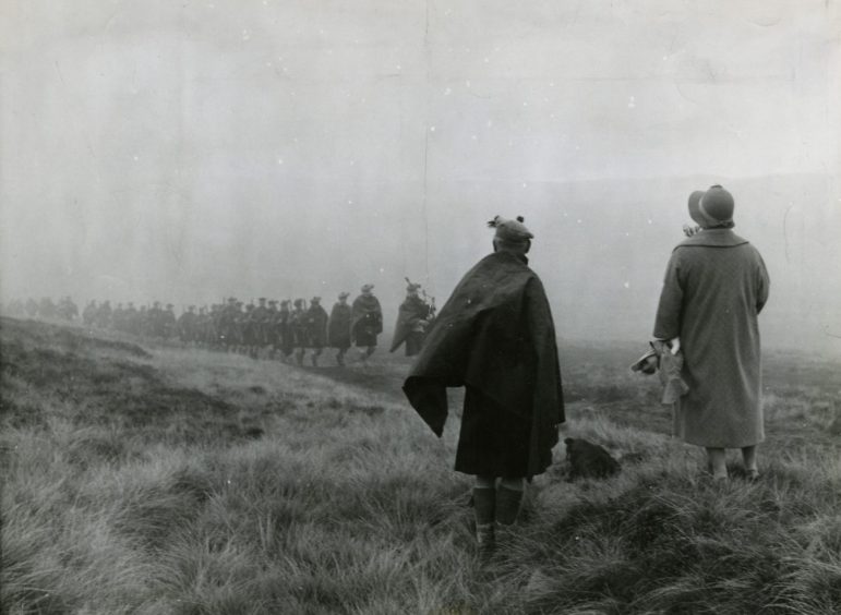 Black Watch troops seen through the haar as the Queen Mother waits at Loch Muick.