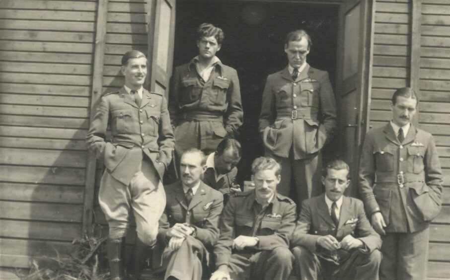 Black and white photo of Sandy Gunn and fellow prisoners standing in RAF uniforms at door to their hut in Stalag Luft III