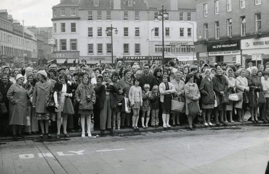 a large crowd in the City Square awaits the arrival of the Queen Mother