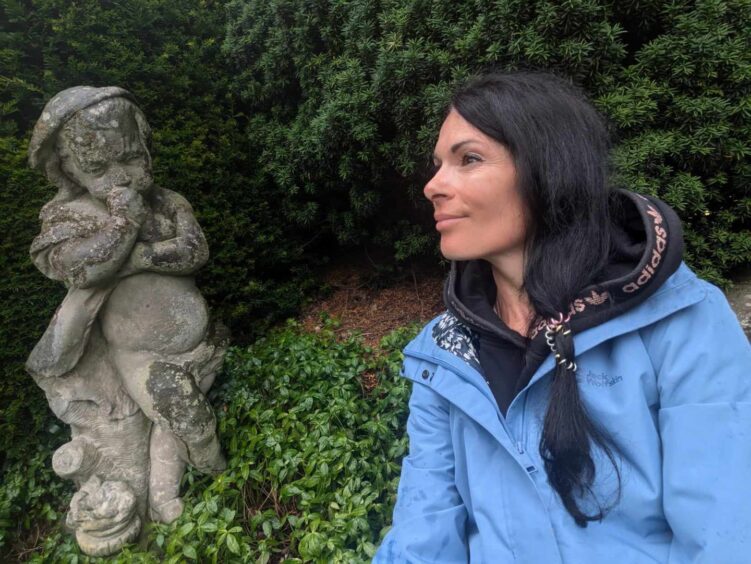 Gayle poses with a statue of a cherub.