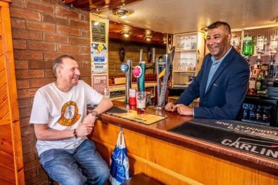 Raj Joshi behind bar with Andy Strike seated enjoying pint