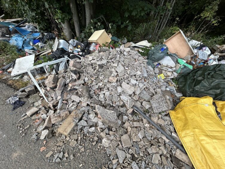 Builders rubble amongst the fly-tipping dumped at the roadside.