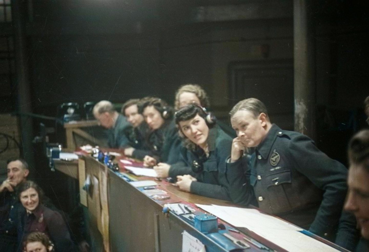 a row of people seated at a bench in the Dundee command centre during the Second World War