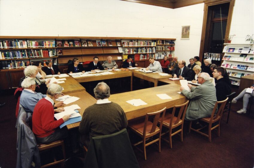 Members sit around some tables at a Community Council meeting in Broughty Ferry Library.